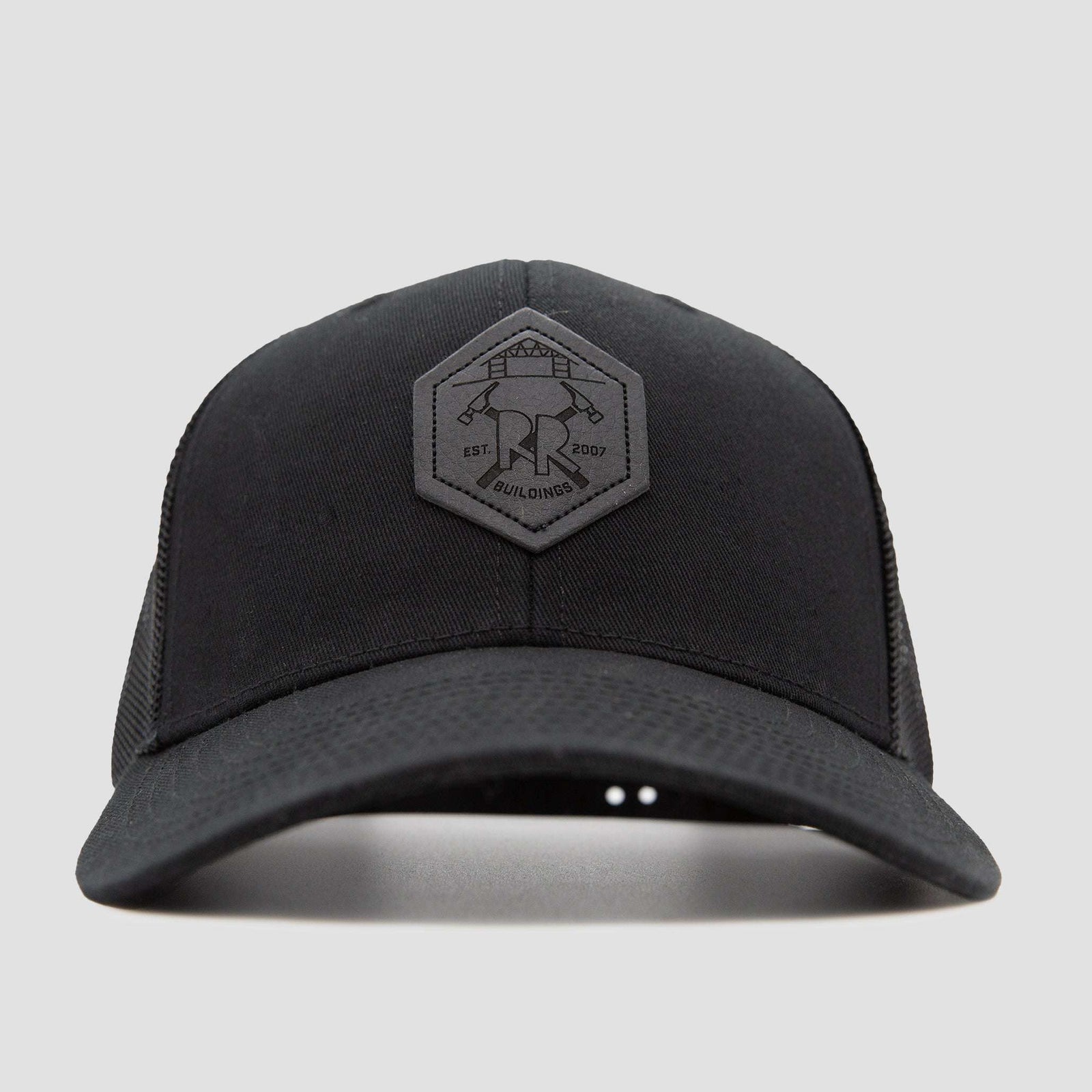 Front view of a black baseball cap with a hexagonal patch on the front, featuring a logo with two crossed hammers and text that reads EST 2007 and BUILDINGS on a plain light gray background.