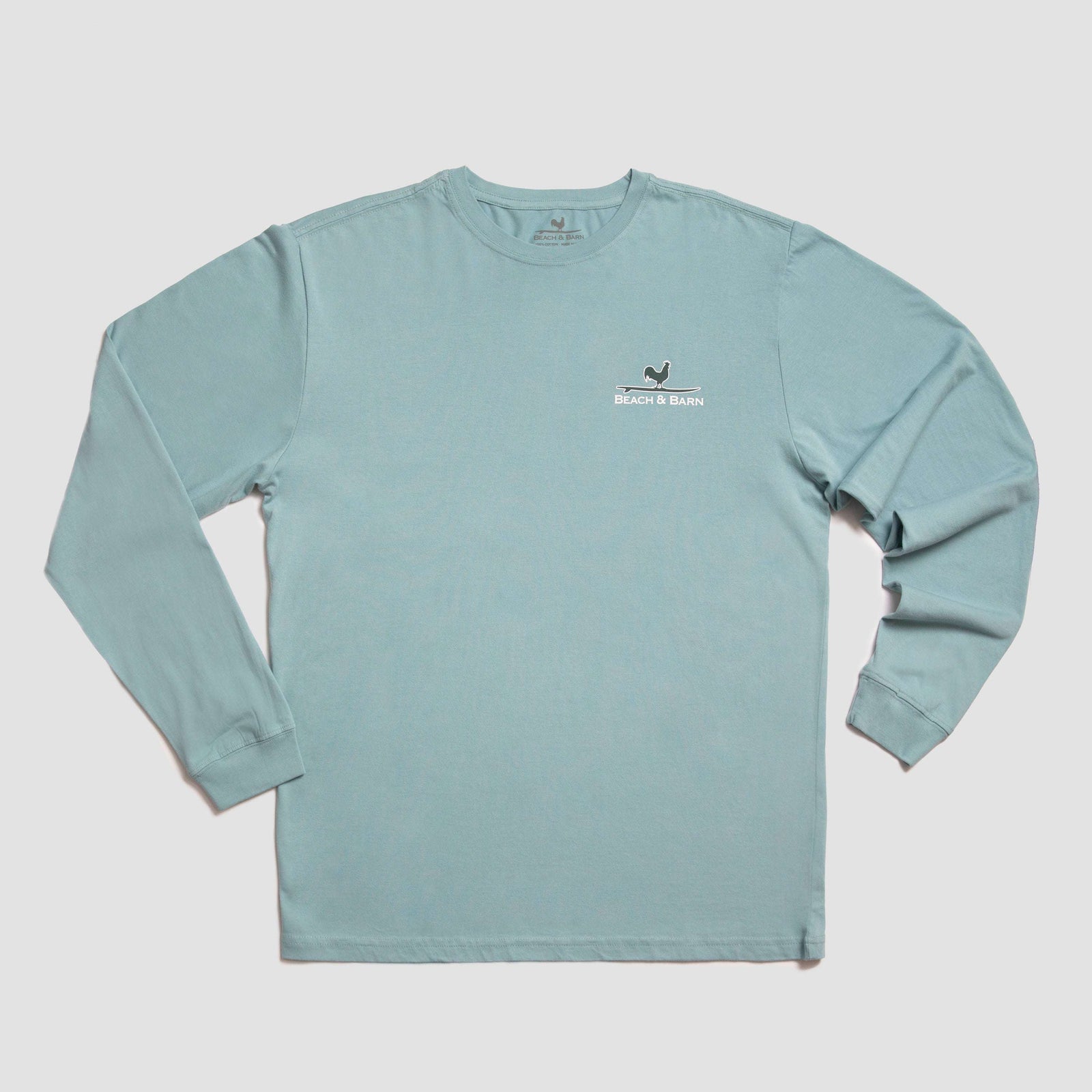 Light blue long-sleeve shirt with a graphic on the back showing a rooster holding a surfboard. Text above and below reads BEACH & BARN and AGRI-COASTAL SUPPLY CO. in dark lettering.