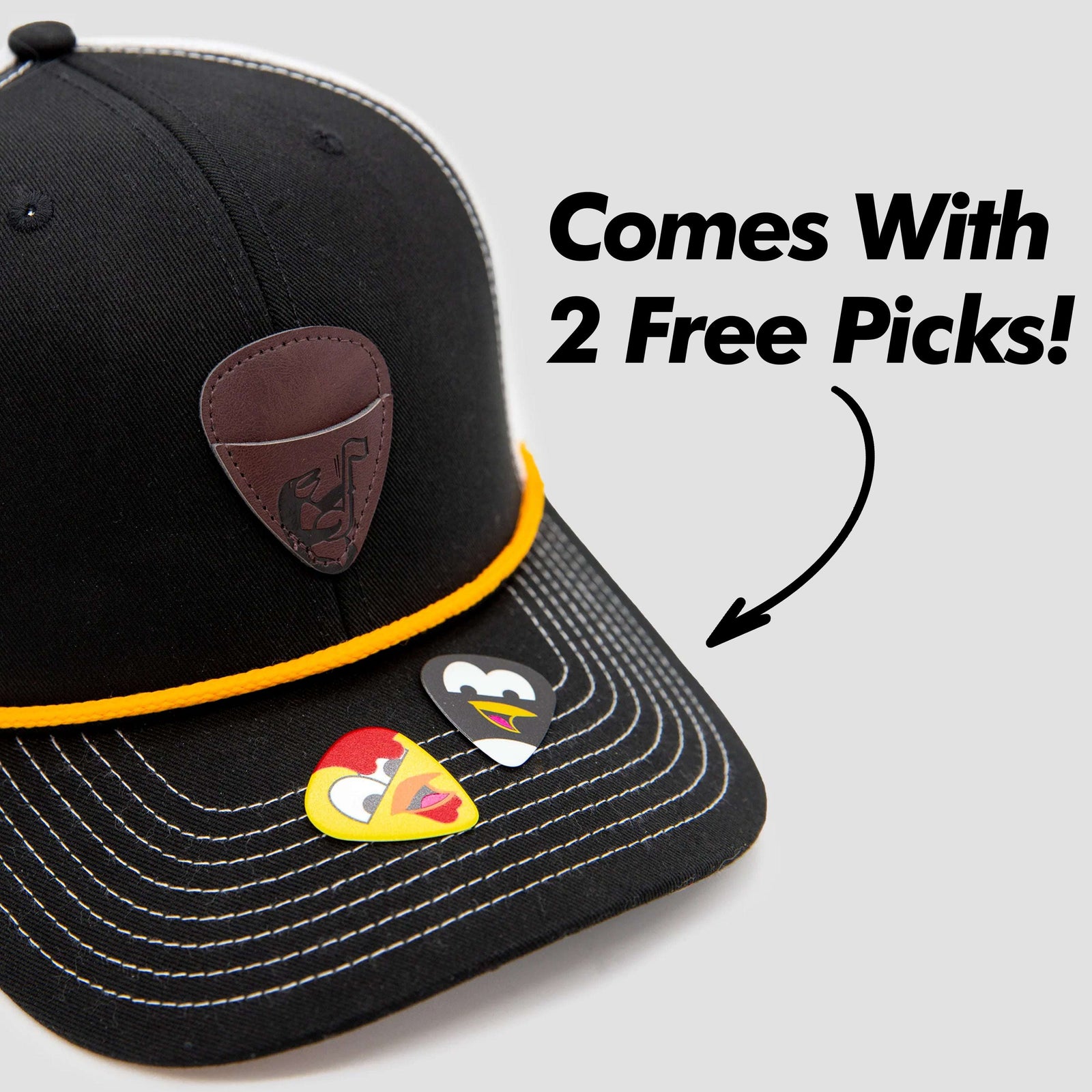 A black and white trucker hat with a yellow rope across the brim and a brown patch featuring a stylized cartoon bird on the front.